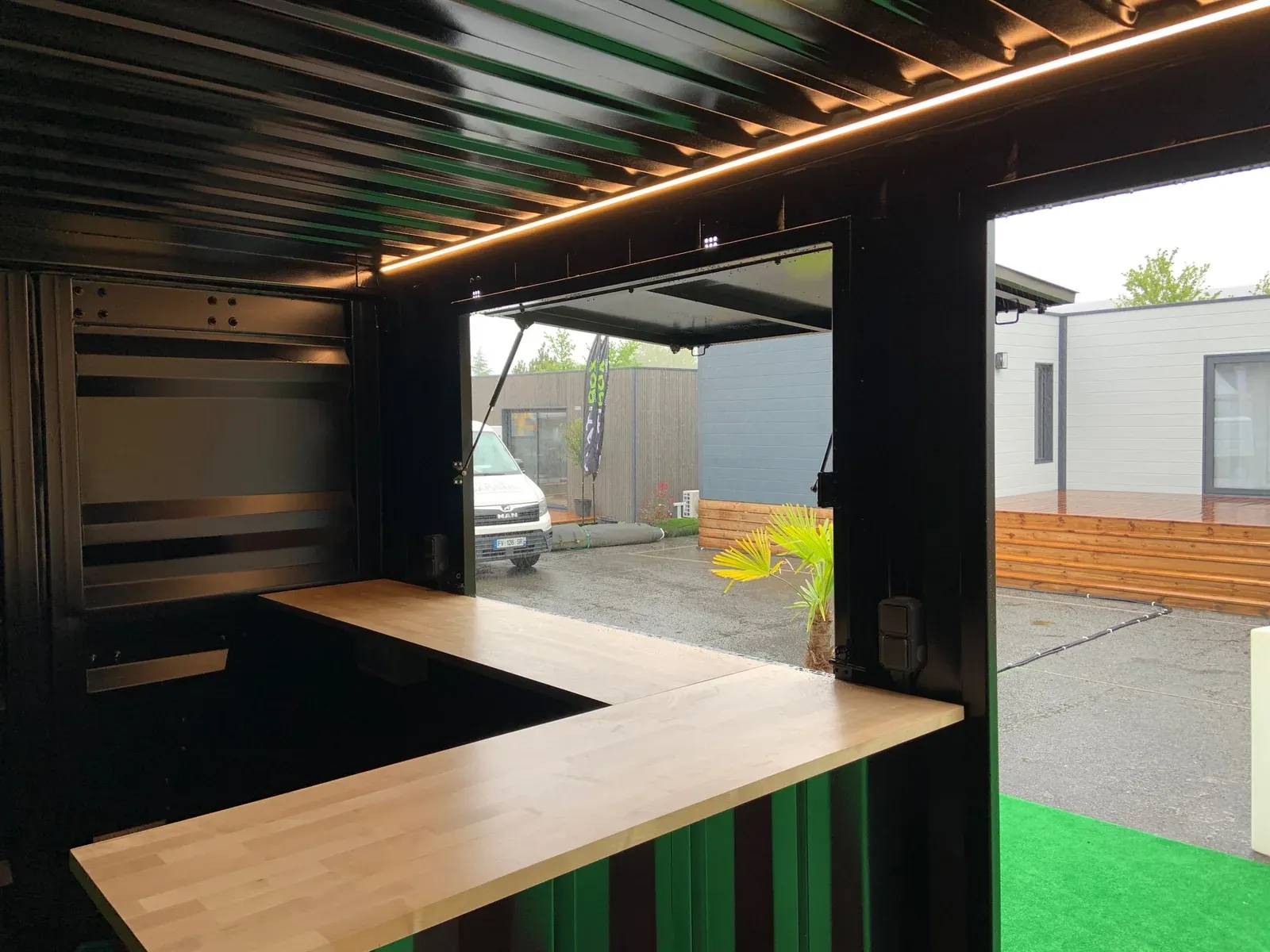 Photo : Conteneur aménagé en bar extérieur, comptoir bois et éclairage
