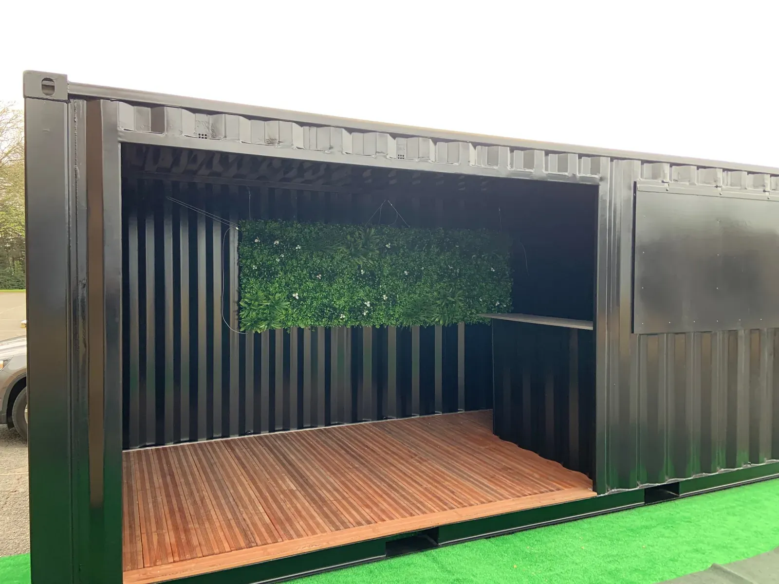 Photo : Conteneur aménagé en espace extérieur couvert, mur végétal et terrasse bois